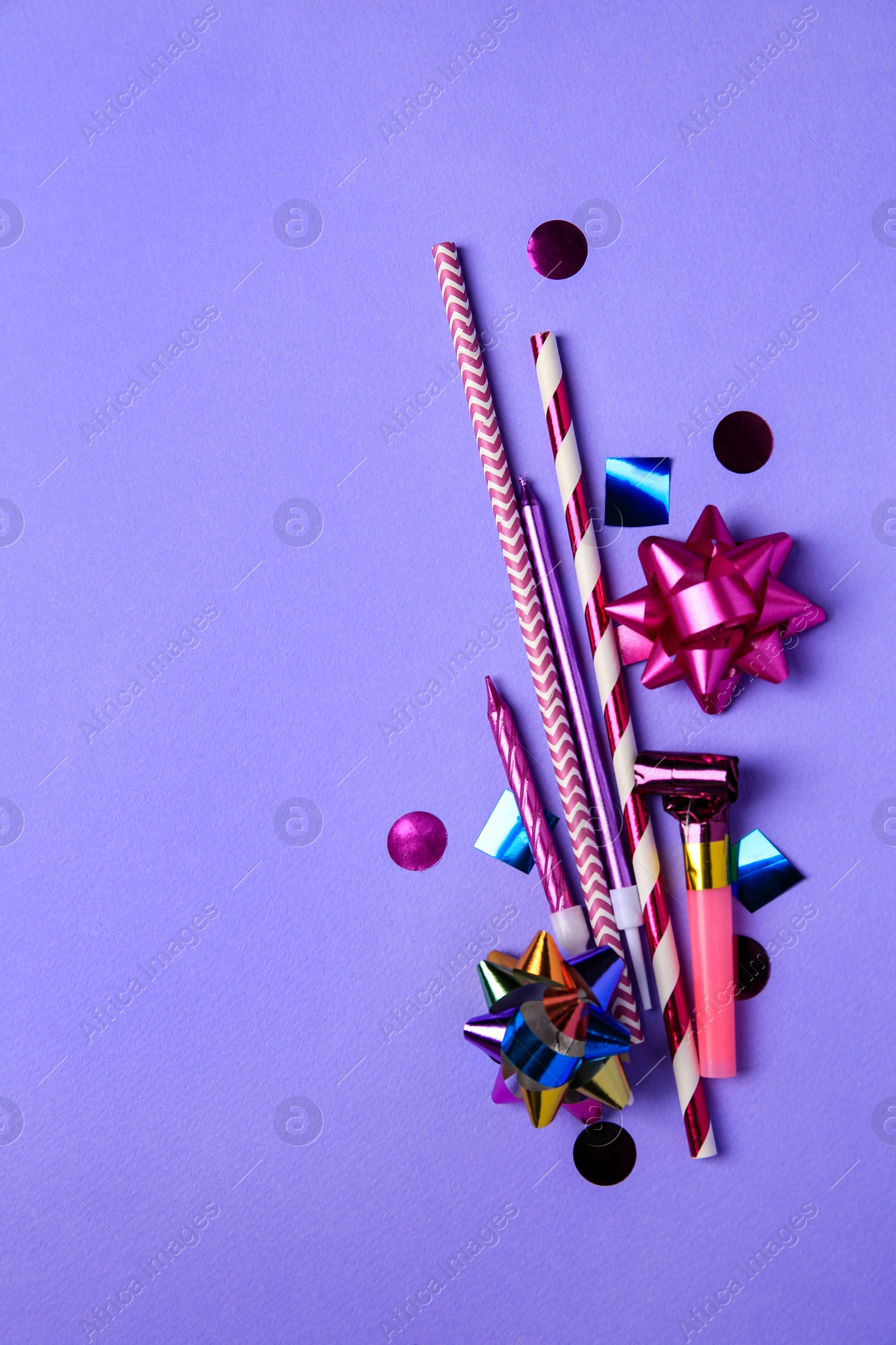 Photo of Party blower, colorful confetti and other festive decor on violet background, flat lay