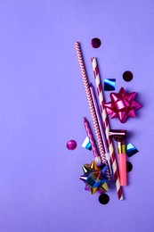 Party blower, colorful confetti and other festive decor on violet background, flat lay