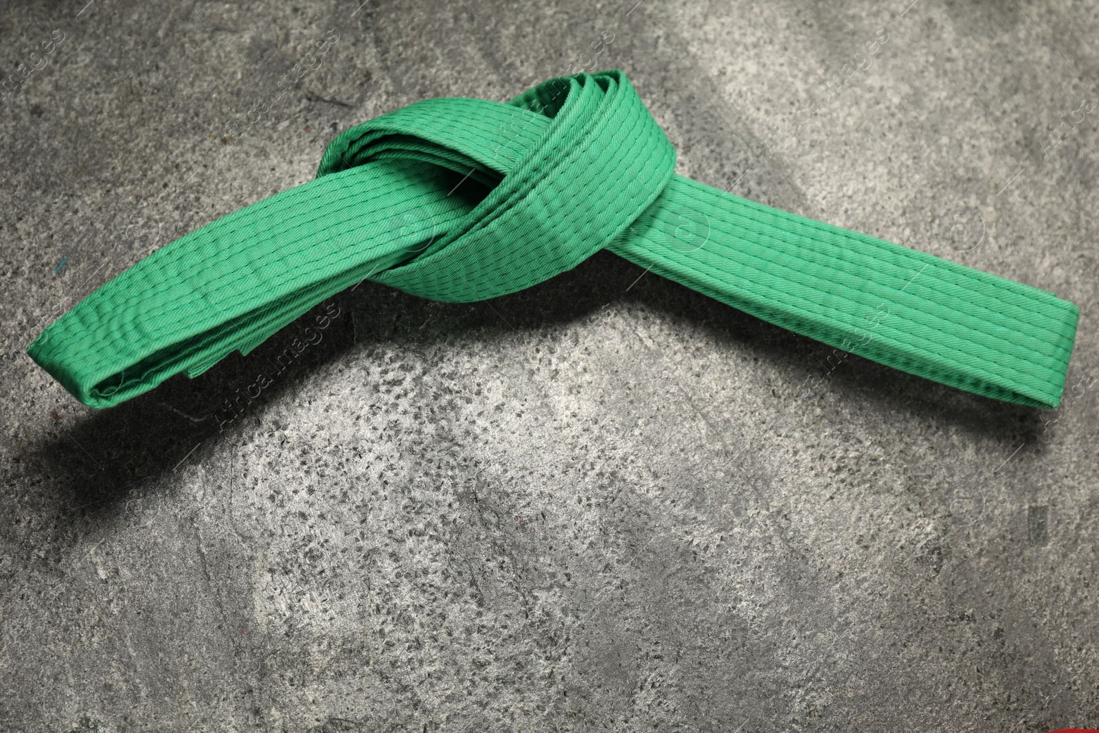 Photo of Green karate belt on gray textured background, top view. Space for text