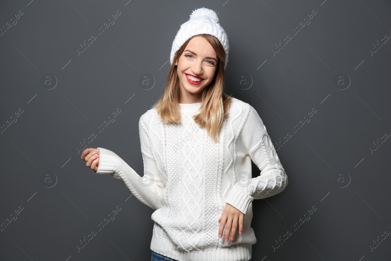 Photo of Beautiful young woman in warm sweater with hat on dark background