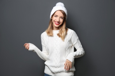 Photo of Beautiful young woman in warm sweater with hat on dark background