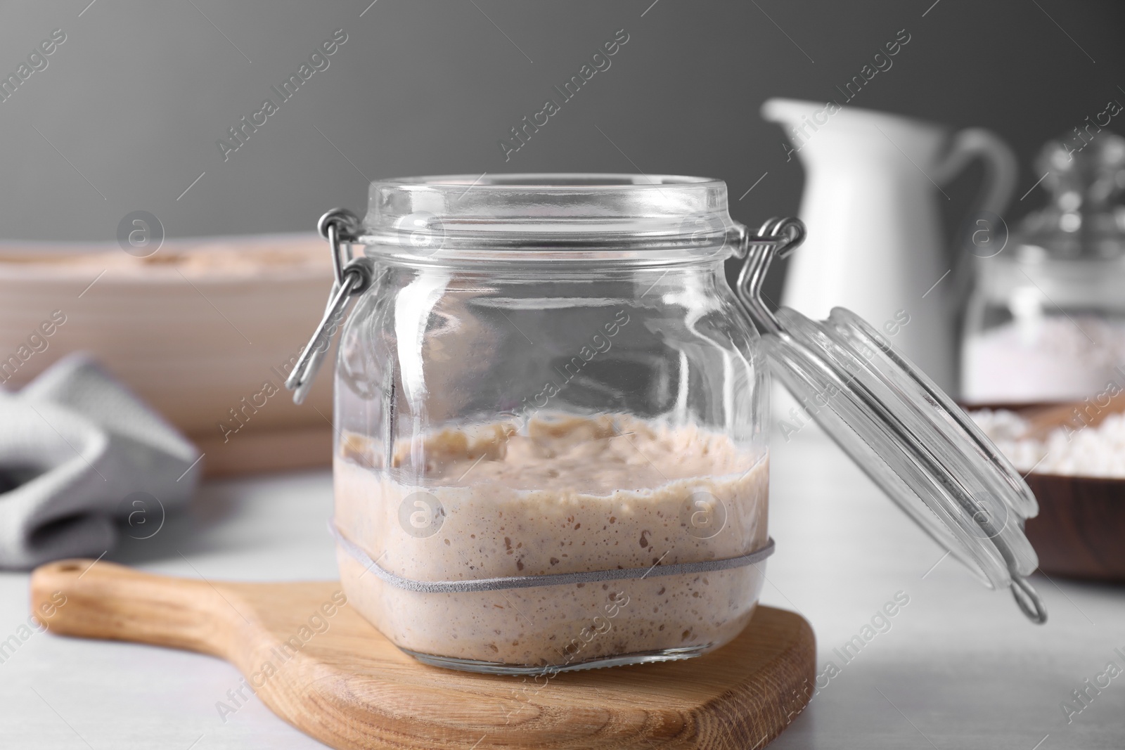 Photo of Sourdough starter in glass jar on light table, closeup