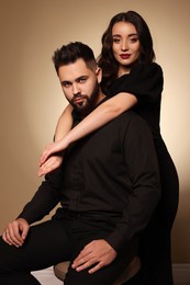 Handsome bearded man with sexy lady on light brown background
