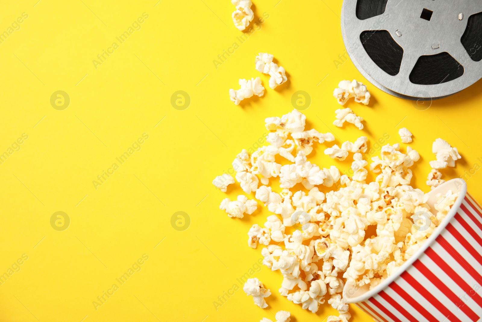 Photo of Flat lay composition with popcorn, reel and space for text on color background. Cinema snack