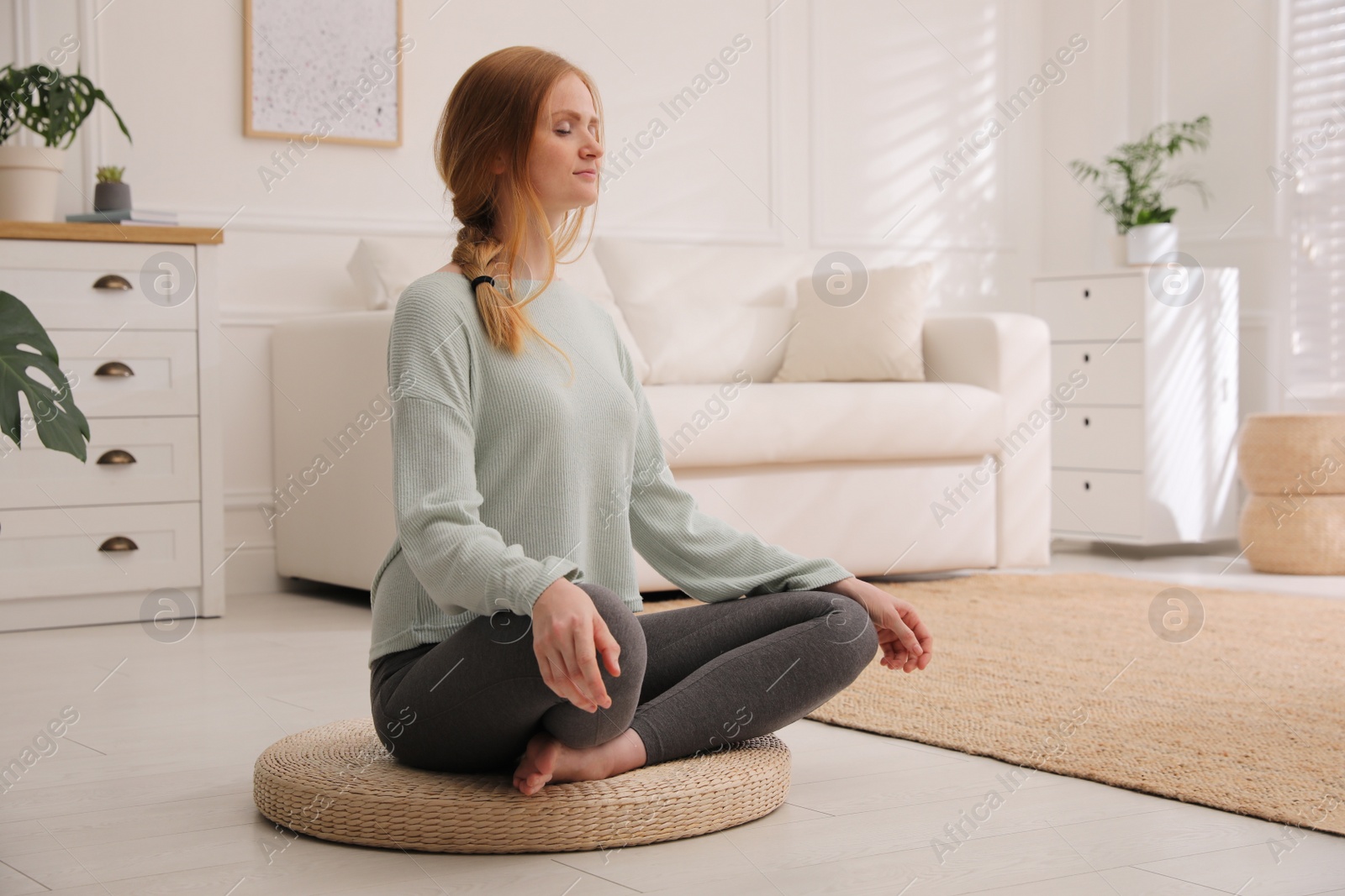 Photo of Woman meditating on wicker mat at home