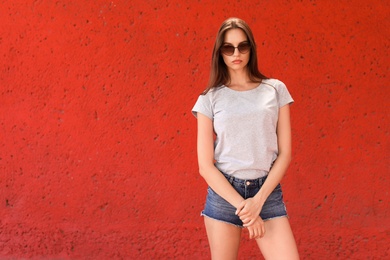 Young woman wearing gray t-shirt near color wall on street