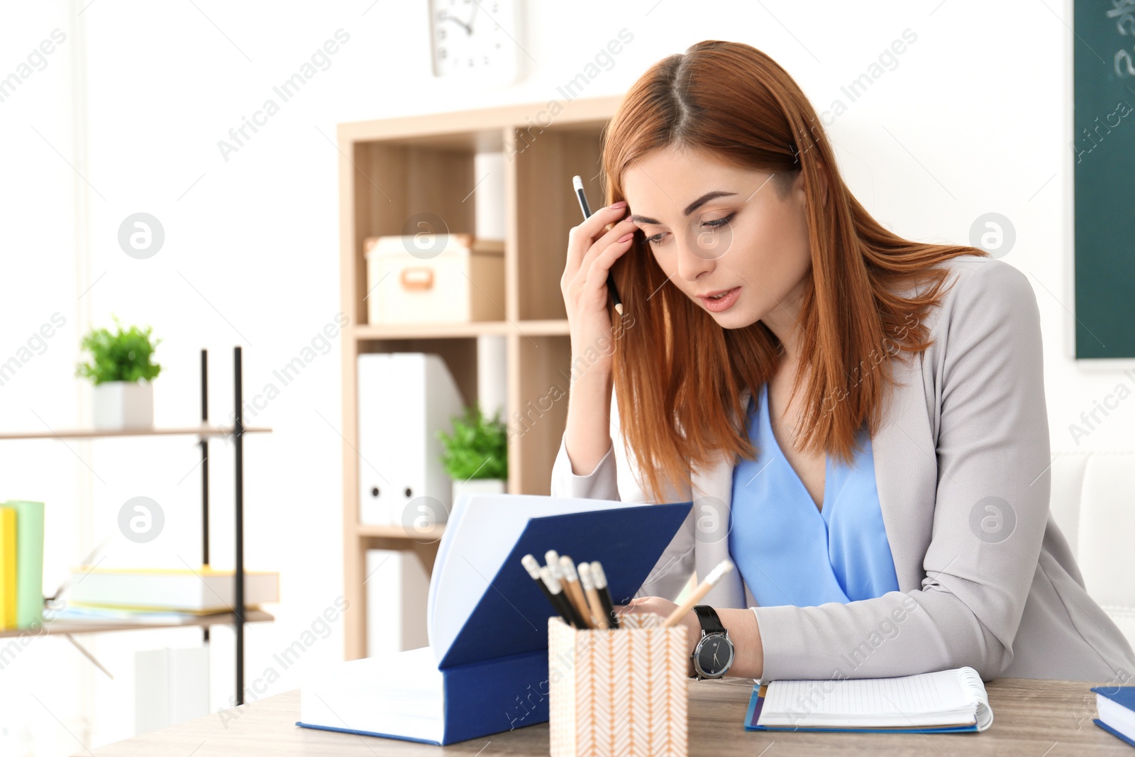 Photo of Beautiful young teacher working at table in classroom