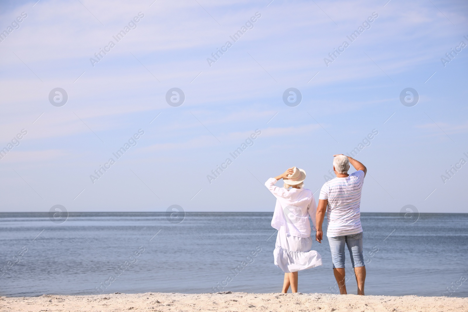 Photo of Mature couple spending time together on sea beach, back view