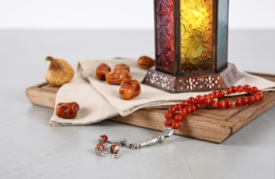 Photo of Muslim lamp, dates and prayer beads on table against white background