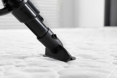 Photo of Disinfecting mattress with vacuum cleaner indoors, closeup