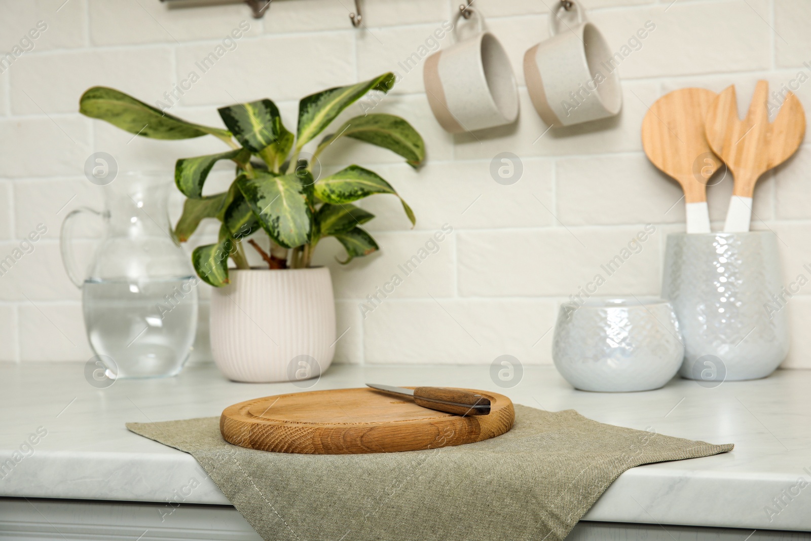 Photo of Clean towel, wooden cutting board and knife on countertop in kitchen