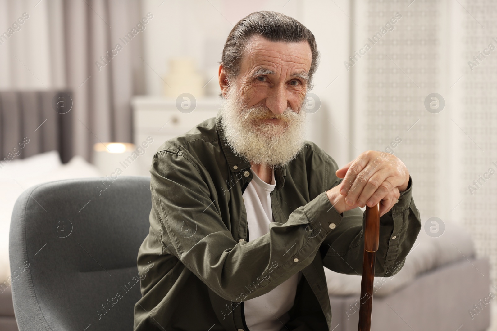 Photo of Senior man with walking cane on chair at home