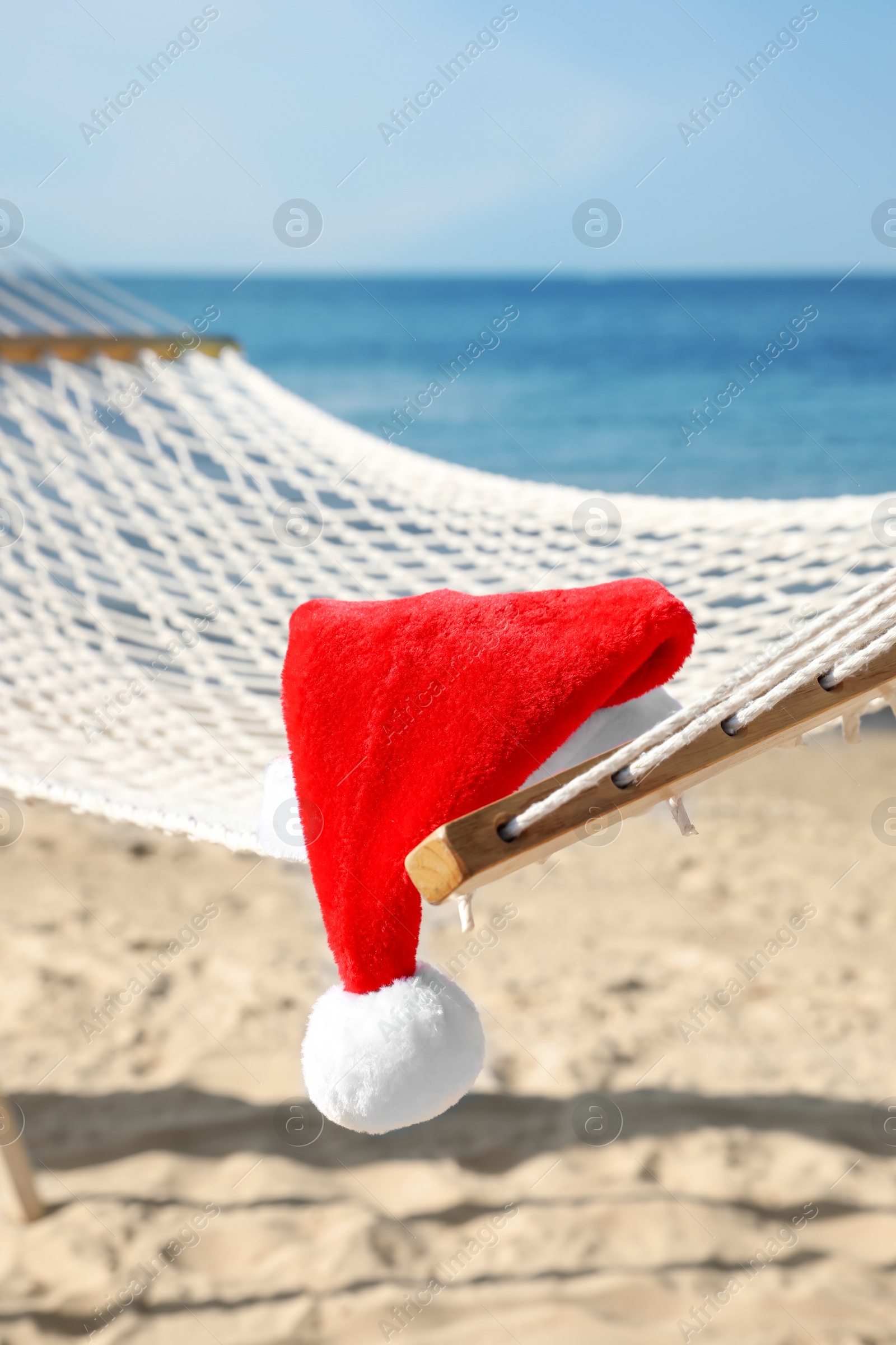 Photo of Rope hammock with Santa's hat on beach, closeup. Christmas vacation