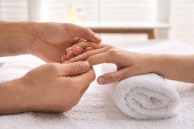 Woman receiving hand massage in wellness center, closeup