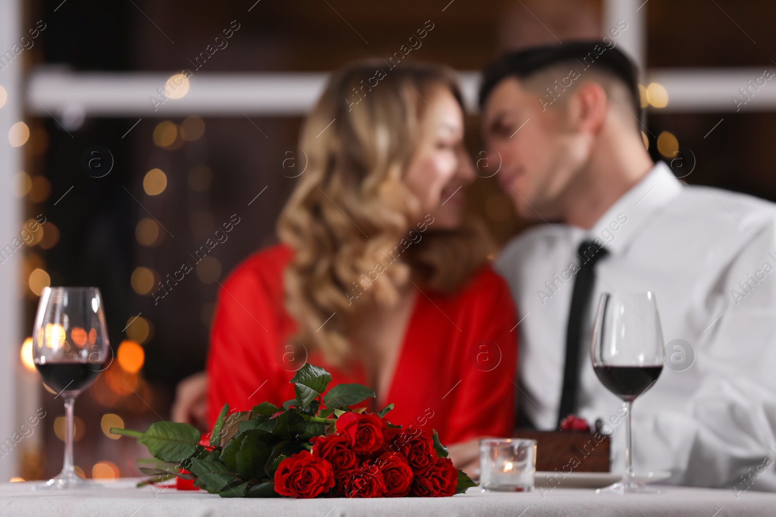 Photo of Lovely couple celebrating Valentine's day in restaurant, focus on table with red roses