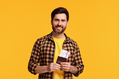 Smiling man with passport and tickets on yellow background