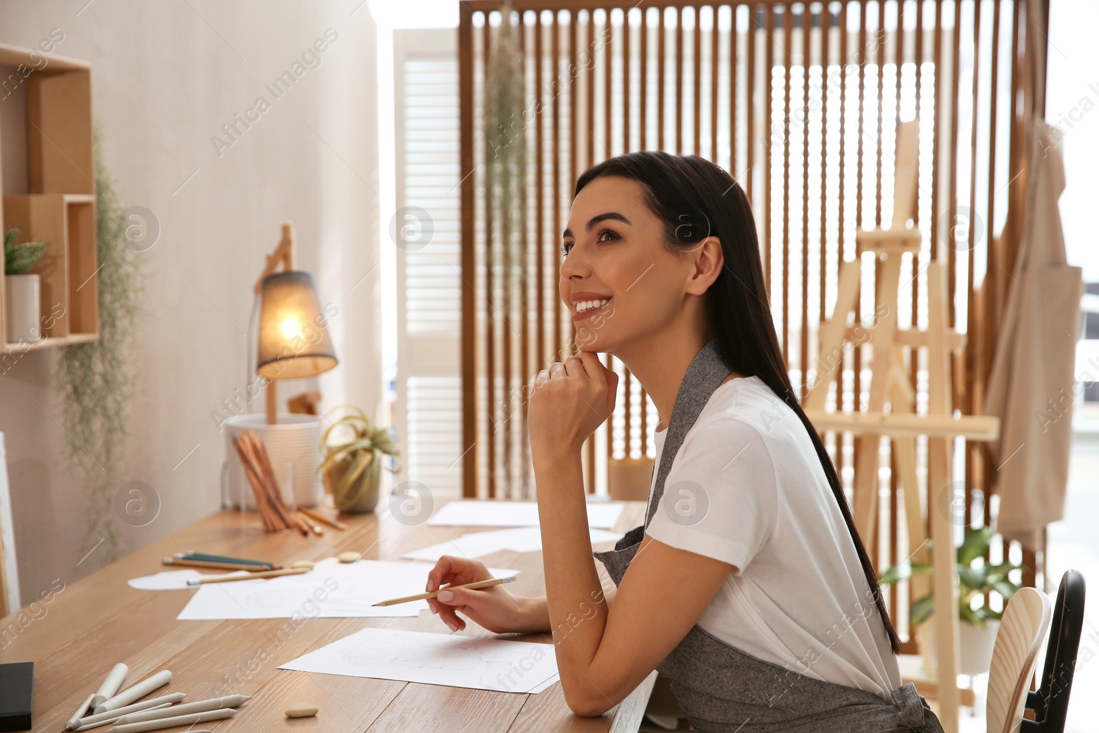 Photo of Young woman drawing with pencil at table indoors