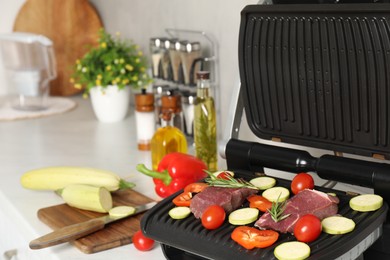 Electric grill and different products on white wooden table, closeup