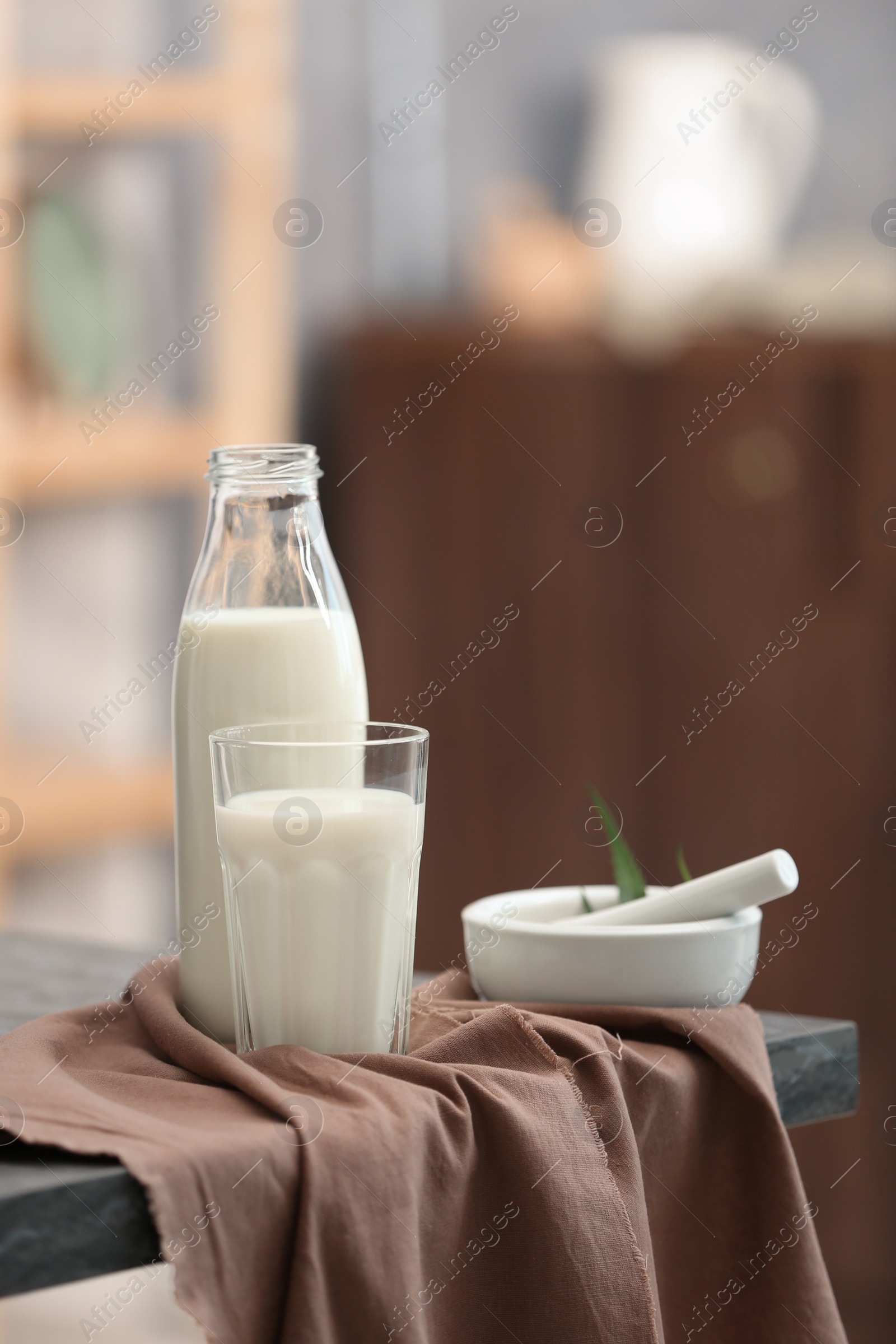 Photo of Glass and bottle with hemp milk on table against blurred background