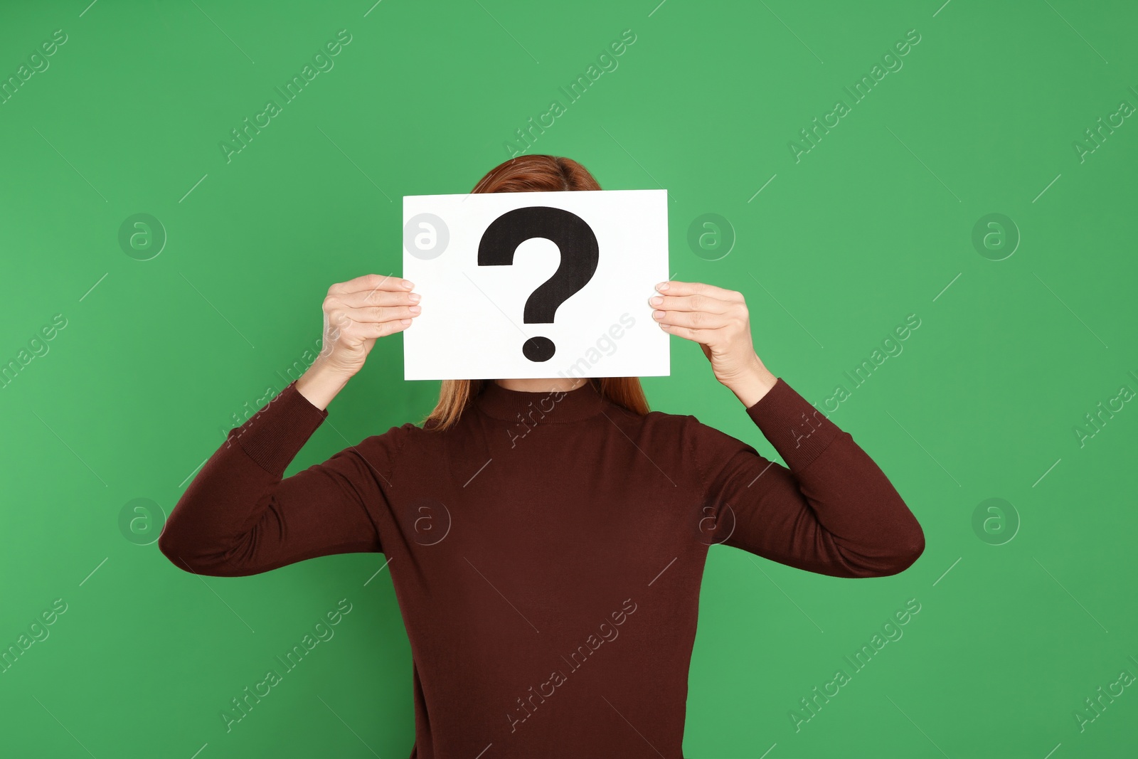 Photo of Woman holding question mark sign on green background