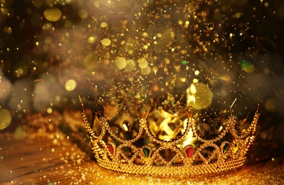 Image of Fantasy world. Beautiful golden crown on table, bokeh effect