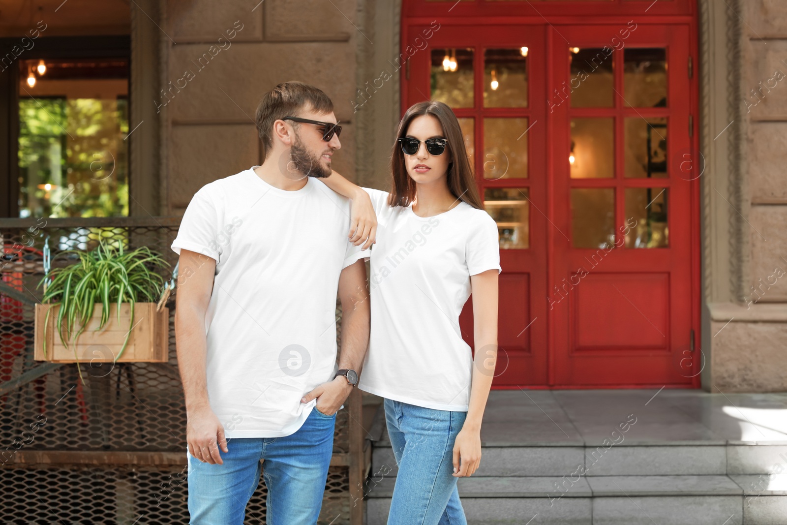 Photo of Young couple wearing white t-shirts on street