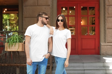 Photo of Young couple wearing white t-shirts on street