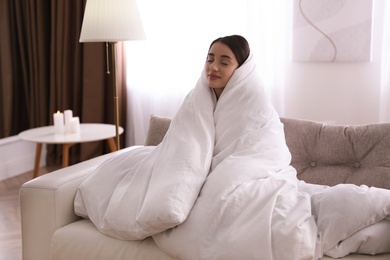 Woman wrapped in blanket resting on sofa