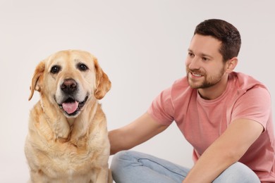 Man with adorable Labrador Retriever dog on light gray background. Lovely pet