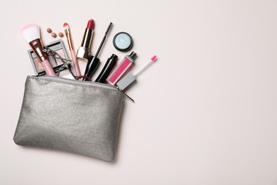 Cosmetic bag with makeup products and accessories on beige background, flat lay. Space for text