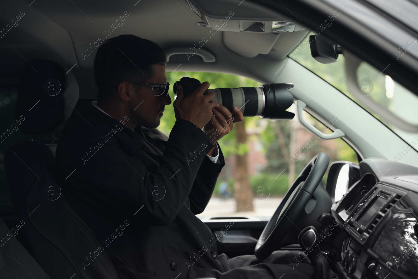 Photo of Private detective with camera spying from car