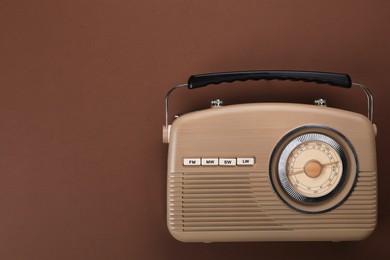 Photo of Retro radio receiver on brown background, top view. Space for text