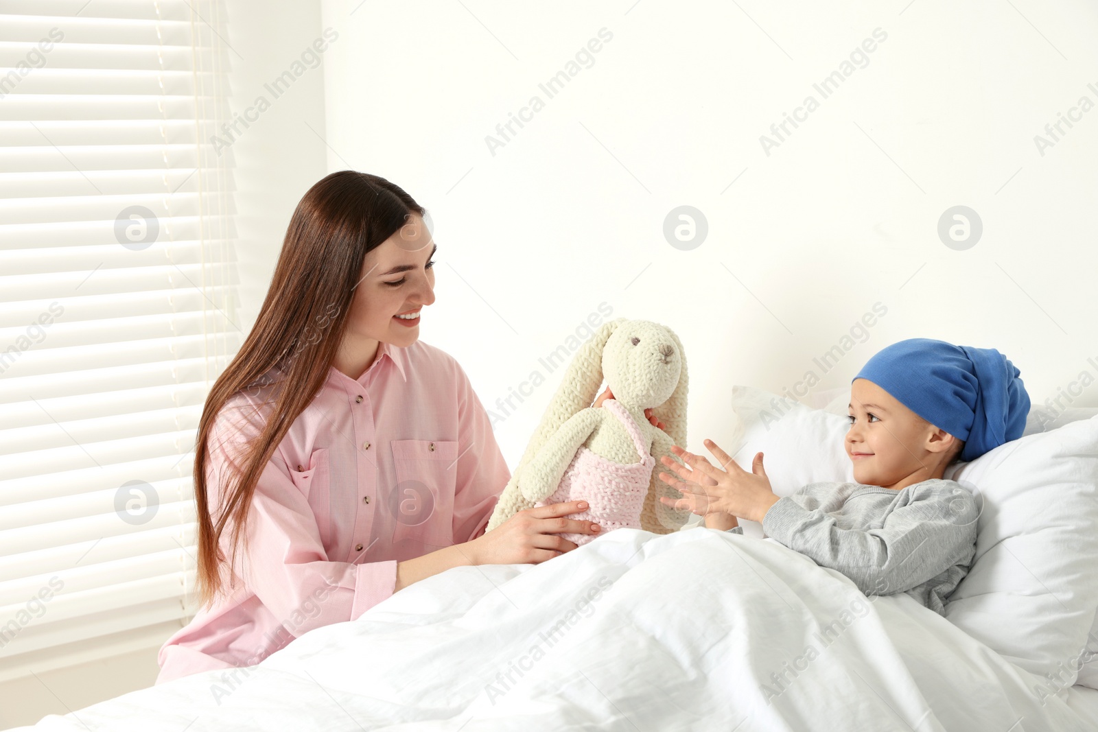 Photo of Childhood cancer. Mother and daughter with toy bunny in hospital