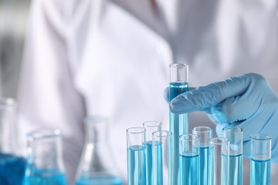 Photo of Scientist taking test tube with light blue liquid in laboratory, closeup. Space for text