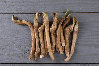 Photo of Fresh raw horseradish roots on grey wooden table, flat lay