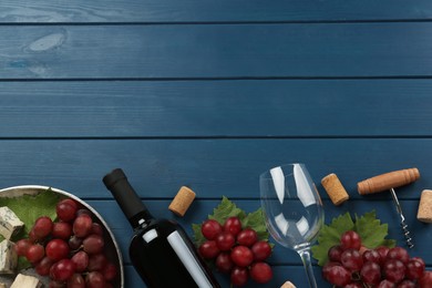 Tasty red wine and snacks on blue wooden table, flat lay. Space for text