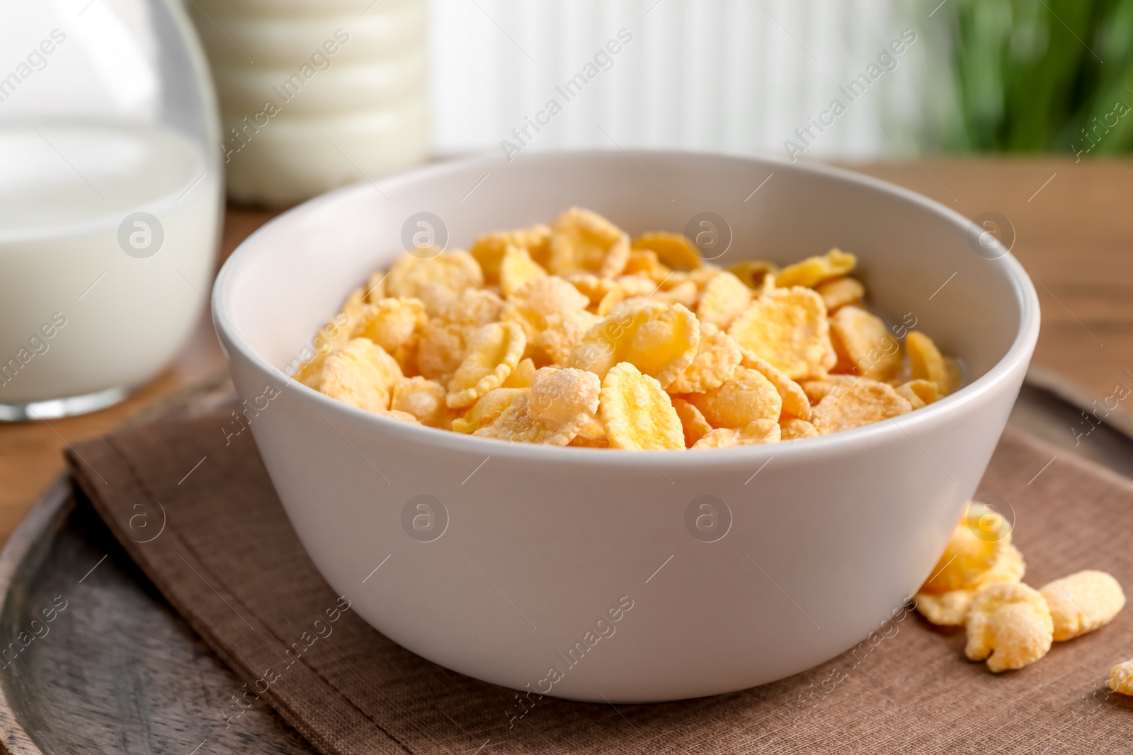 Photo of Tasty cornflakes with milk in bowl on table, closeup