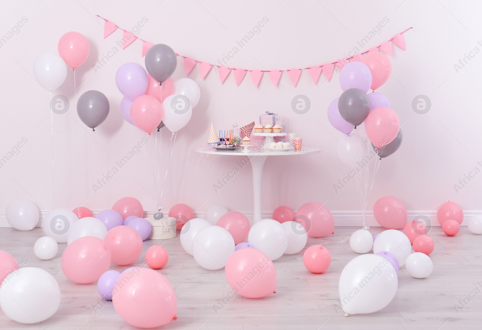 Photo of Party treats and items on table in room decorated with balloons