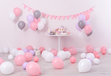 Party treats and items on table in room decorated with balloons