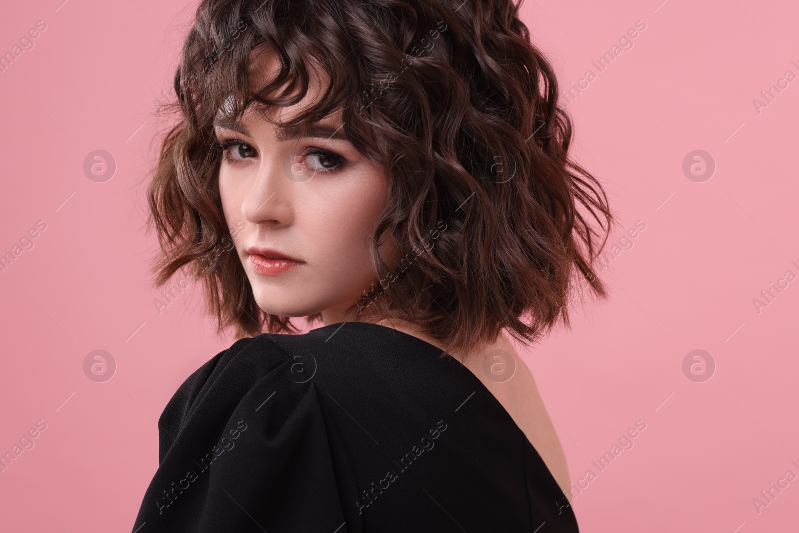 Photo of Portrait of beautiful young woman with wavy hairstyle on pink background