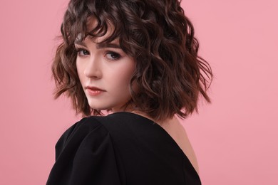 Photo of Portrait of beautiful young woman with wavy hairstyle on pink background