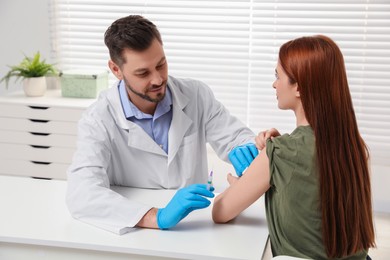 Doctor giving hepatitis vaccine to patient in clinic