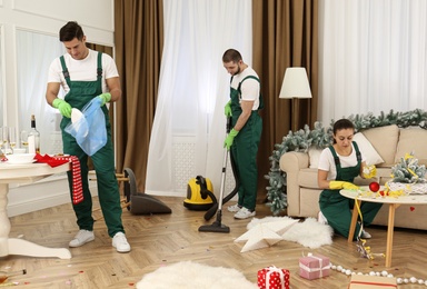Photo of Cleaning service team working in messy room after New Year party