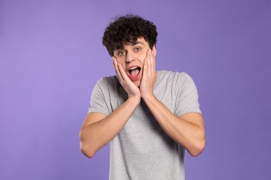 Photo of Portrait of shocked young man on violet background