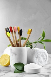 Photo of Bamboo toothbrushes and bowl of baking soda on white marble table