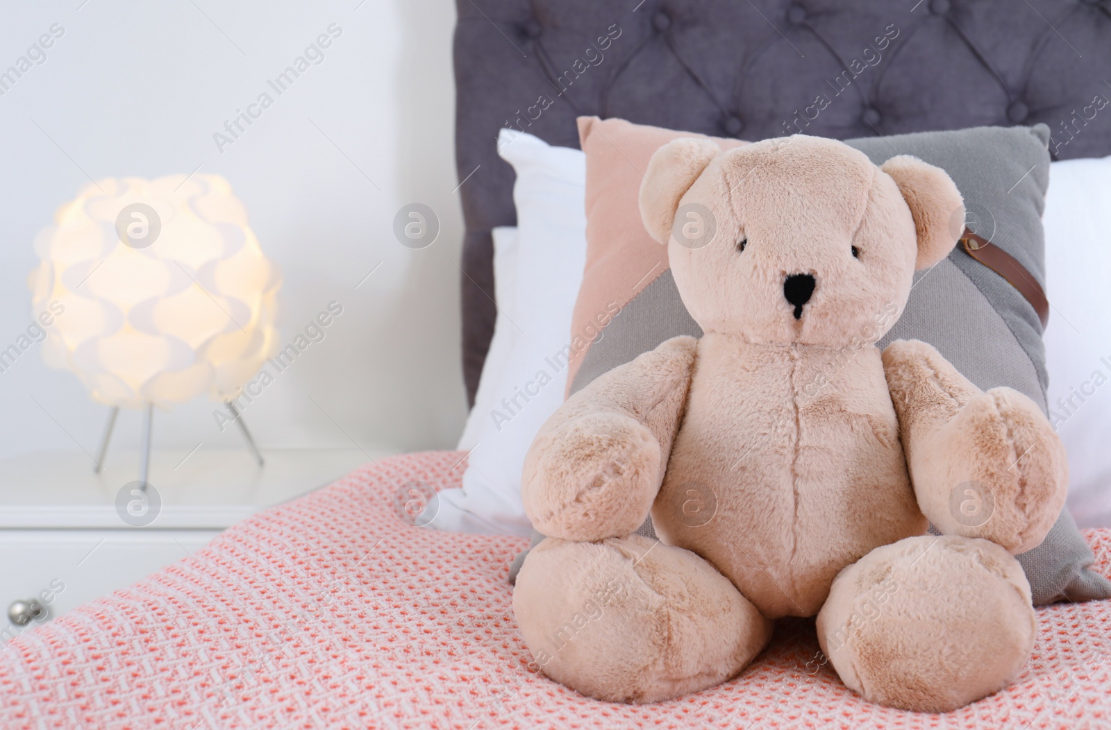 Photo of Cute teddy bear sitting on bed indoors. Space for text