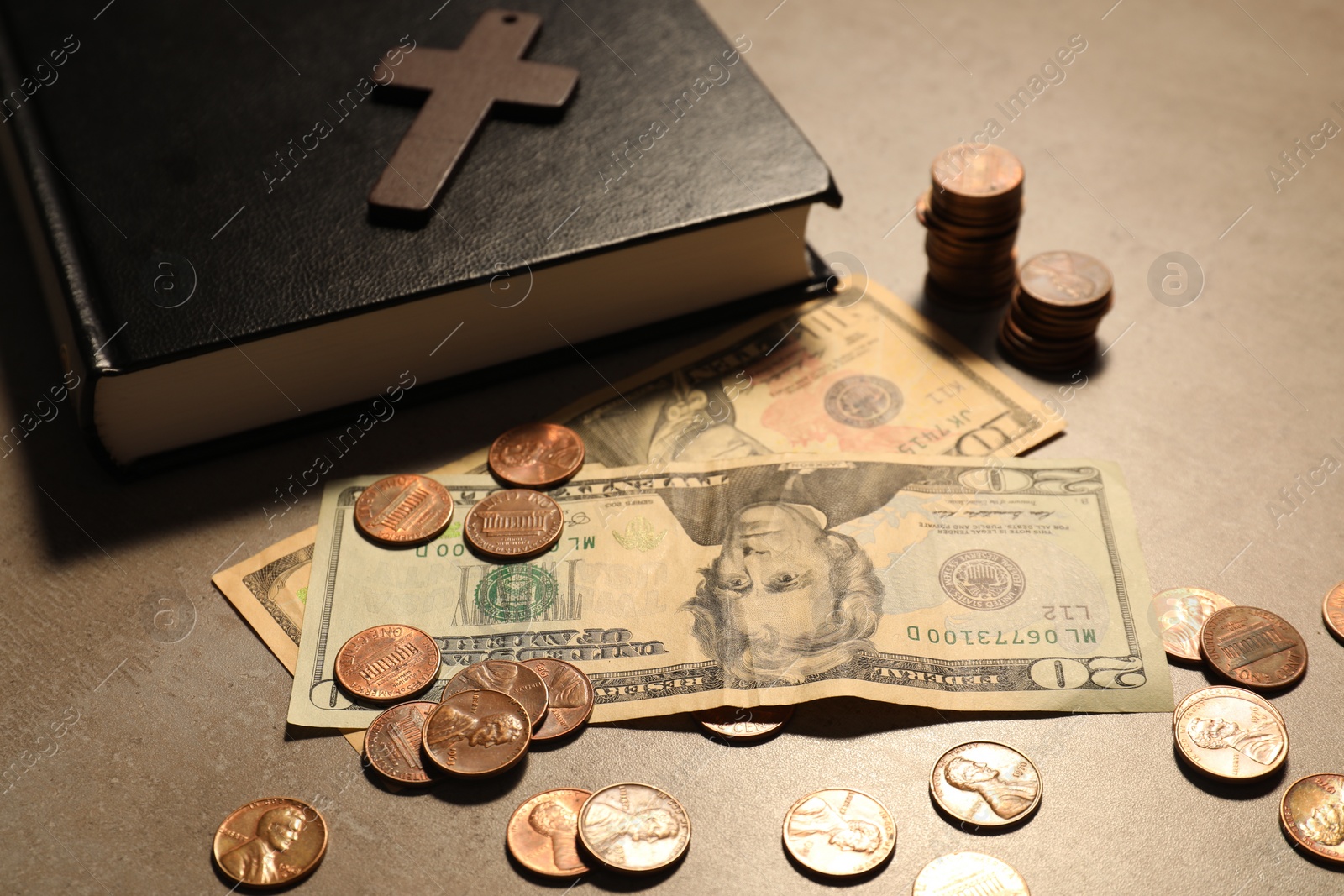 Photo of Donate and give concept. Coins, Bible, cross and dollar banknotes on grey table