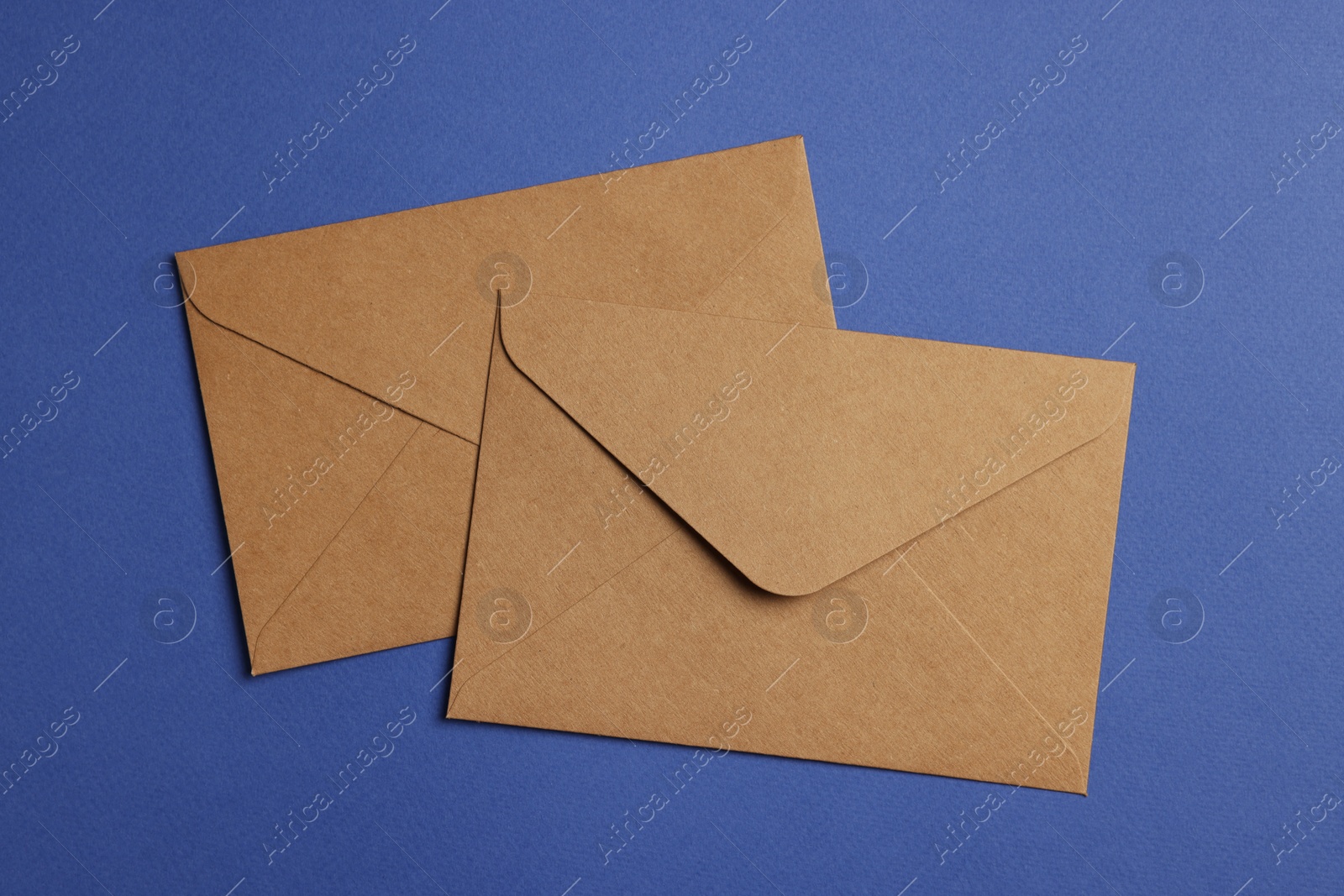 Photo of Envelopes made of parchment paper on blue background, flat lay