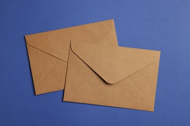 Photo of Envelopes made of parchment paper on blue background, flat lay