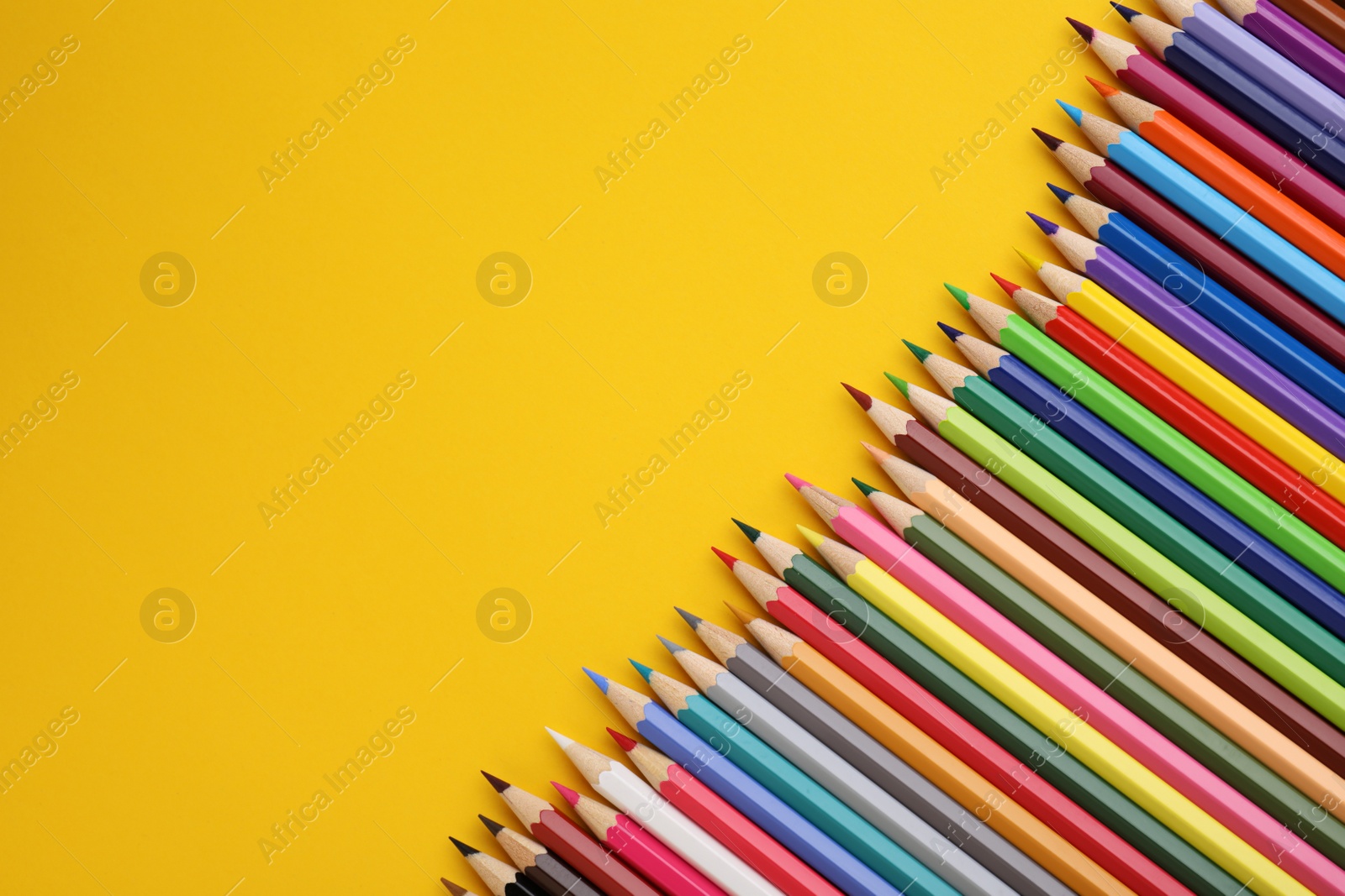 Photo of Colorful wooden pencils on yellow background, flat lay. Space for text